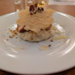 Een risotto met maiskip in serranoham, met een sinaasappel compote en een chipje van Parmezaanse kaas.